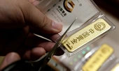 A man cuts open the bag after he bought 50 gram gold bars as an investment in Beijing, China, Aug. 5, 2019.