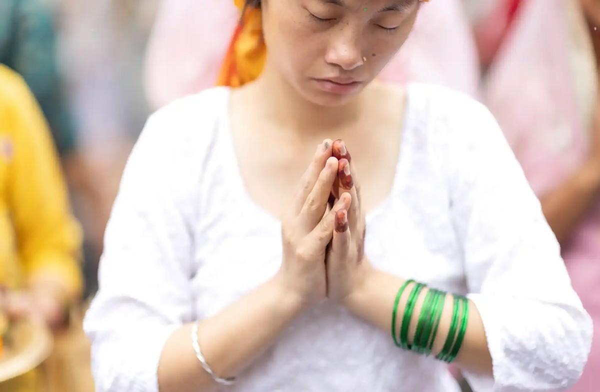 A woman in white with green bracelets on her left hand prays during a Sarwan Brata (fast) offering to Lord Shiva, the Hindu god of creation and destruction, at the Pashupatinath temple in Kathmandu.
