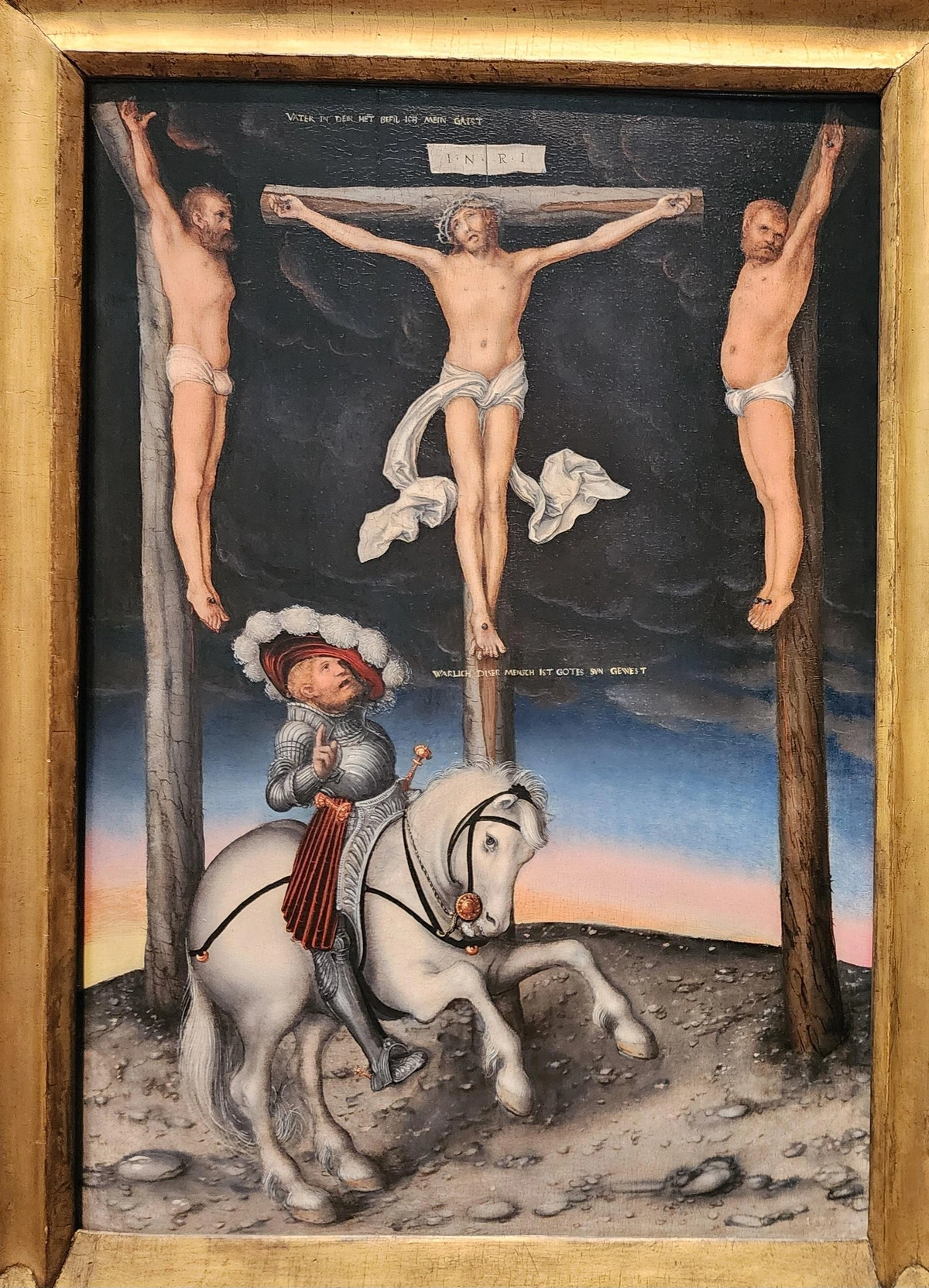 crucifixion scene with the two thieves close to Jesus' left and right. below them is a centurion in anachronistic wide hat and suit of iron riding a white horse. above him is the caption

WARLICH DISER MENSCH IST GOTES SVN...

above jesus is the caption

VATER IN DEIN HET BEFIL ICH MEIN GAIST