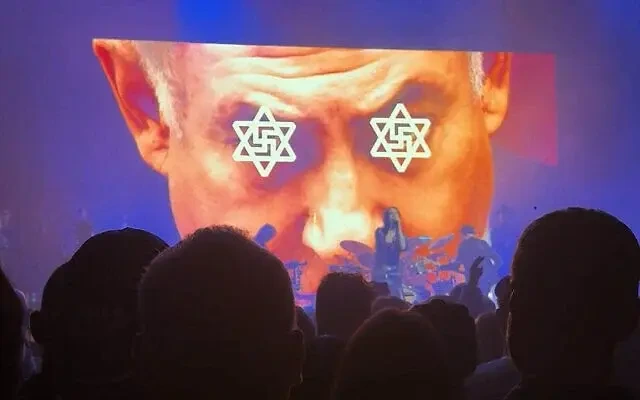 A video shown on stage of with an image of swastikas in the centre of Stars of David superimposed over the eyes of Prime Minister Benjamin Netanyahu, during a performance by British band Primal Scream in London, December 8, 2025. (Screenshot/X)