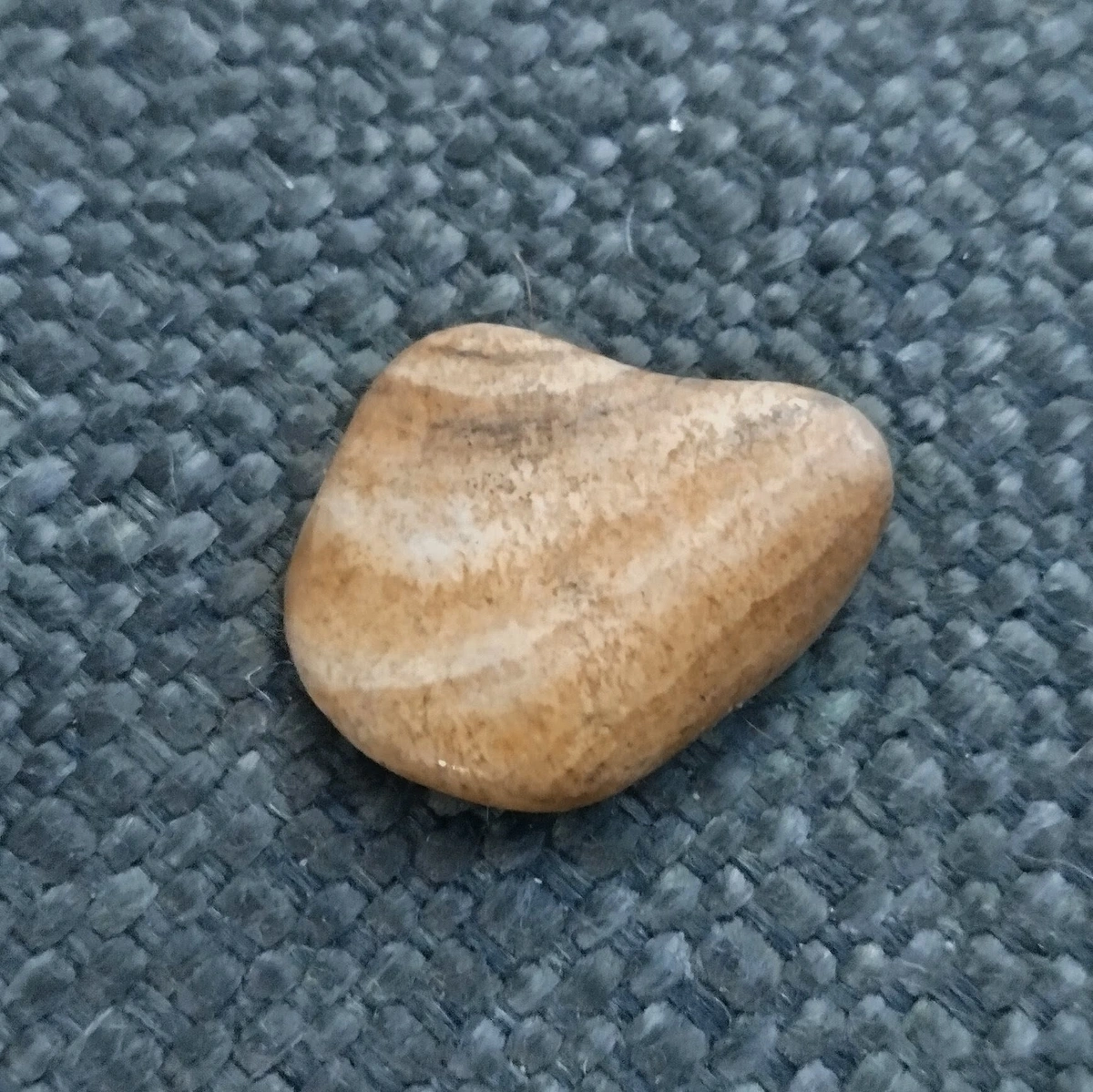 A smooth, flat, tan rock with striations of paler and darker lines.