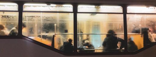 This image shows the inside of a bus or train. The window is foggy, and there are silhouettes of several people seated inside, suggesting it might be crowded or during cold weather. The lighting is warm, creating a cozy atmosphere despite the fogged-up windows.