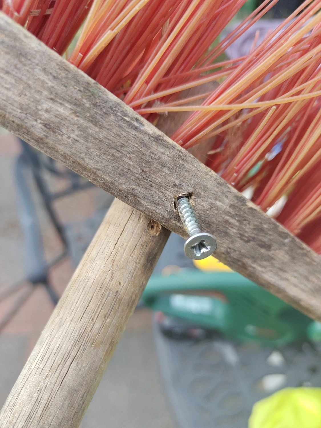 Photograph of an aging broom with a shiny screw holding the bottom to the handle.