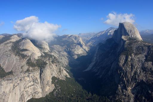 The eastern end of Yosemite Valley, with Half Dome under blue skies with a few small, low puffy clouds.