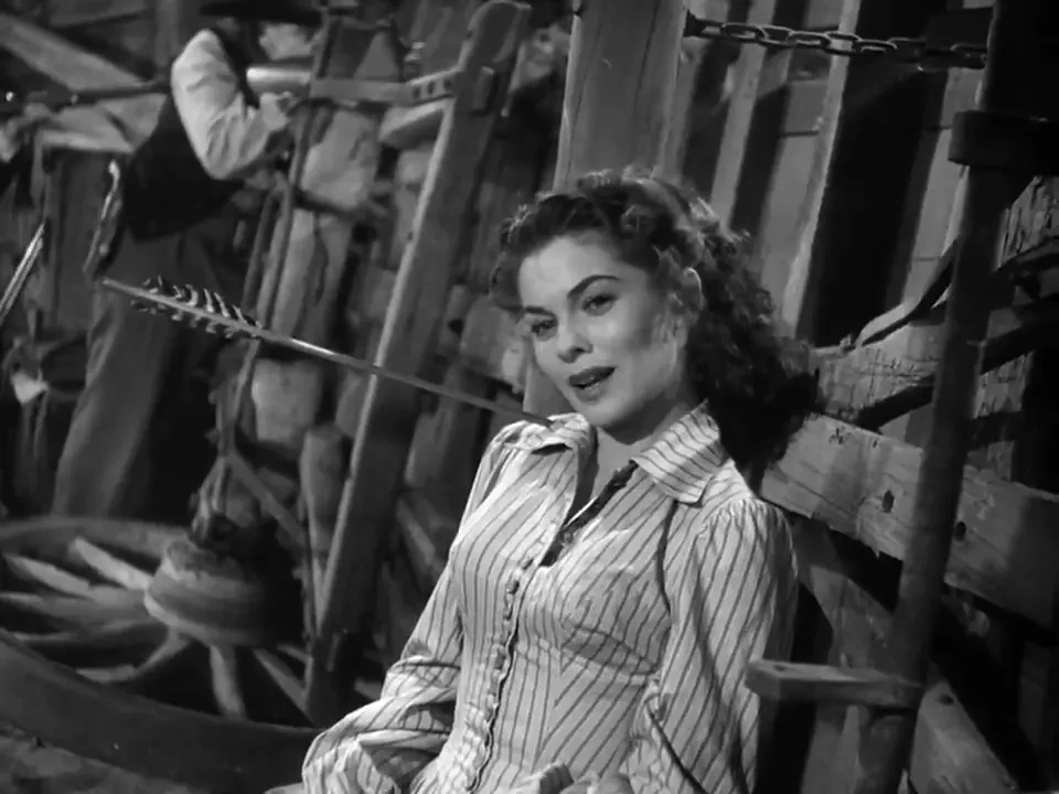 A woman sat against some timbers, an arrow sticking out of her shoulder