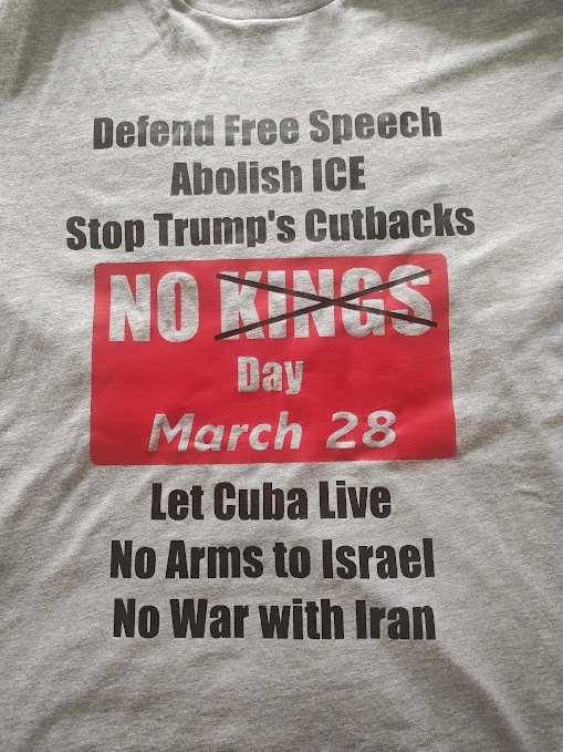Photo of gray tshirt with black lettering and red box with cutout letters 

[black text]
Defend Free Speech 
Abolish ICE
Stop Trump's Cutbacks 

[red box with white cutout text]
No Kings [Kings crossed out with X]
Day 
March 28

[black text]
Let Cuba Live 
No Arms To Israel 
No War With Iran 
