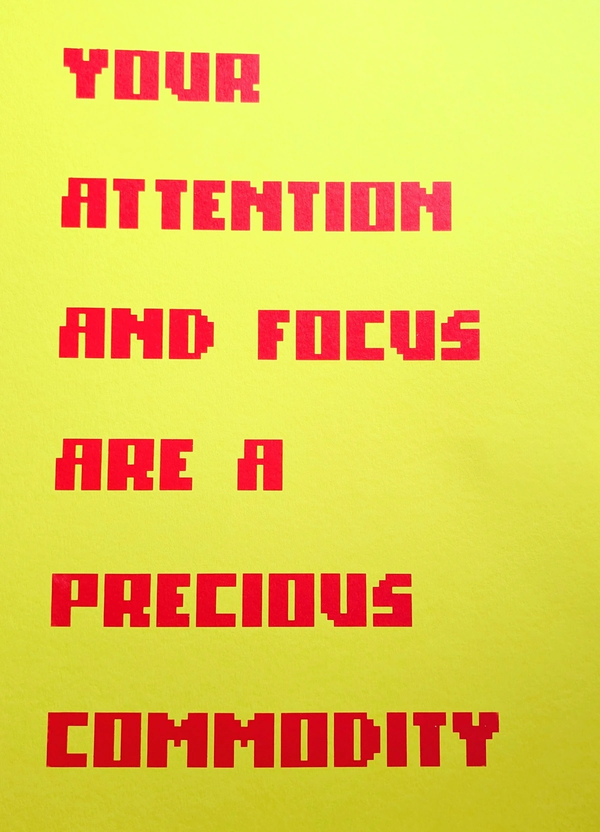 Bright red, pixelated text on a yellow field that reads, "YOUR ATTENTION AND FOCUS ARE A PRECIOUS COMMODITY"