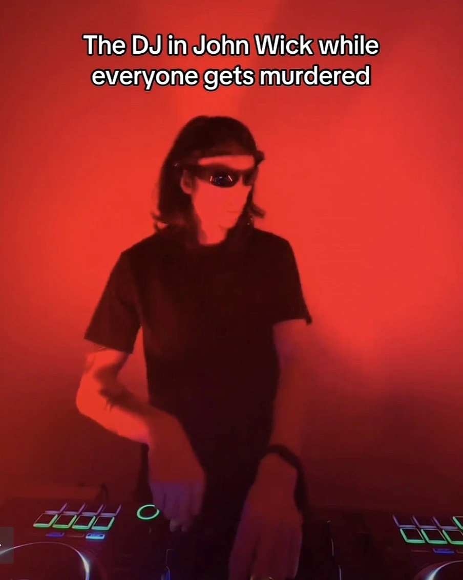 Photo of a DJ in a red room with the caption “The DJ in John Wick while everyone gets murdered”