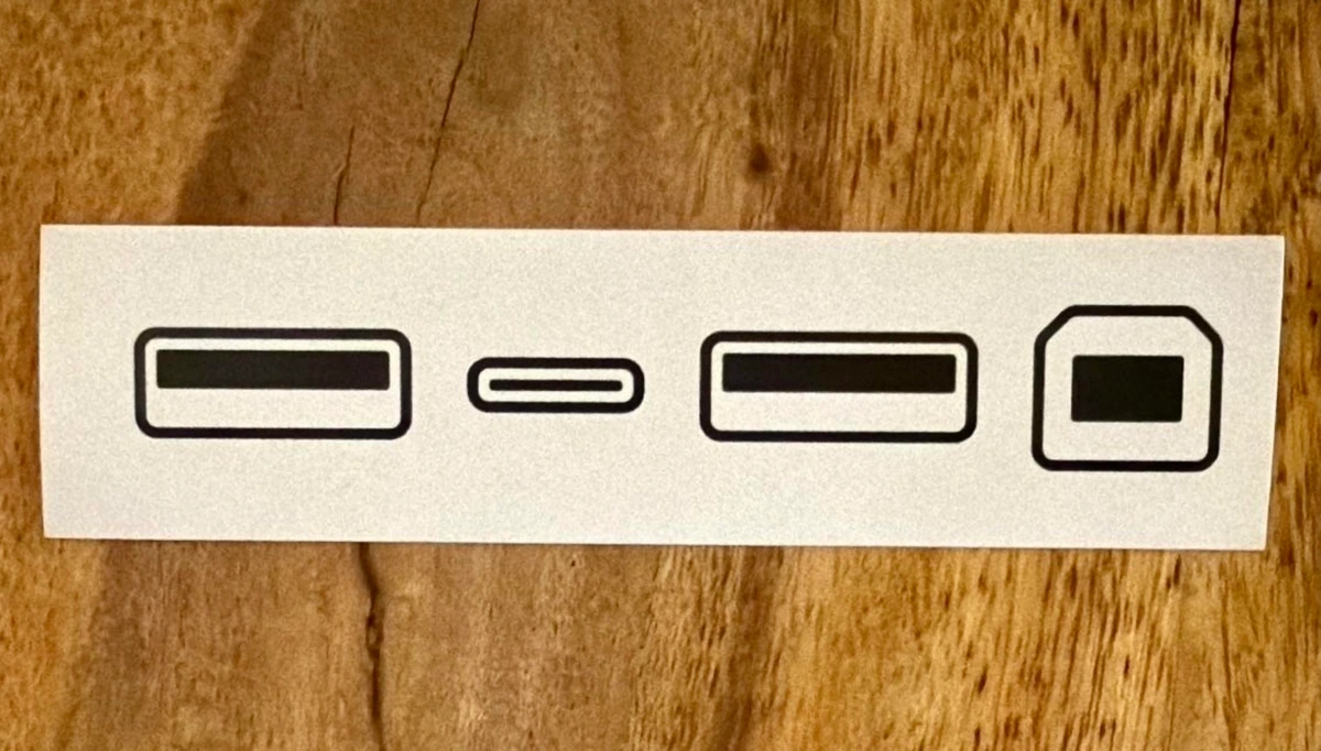 A printed card on a wooden surface displaying various shapes: two rectangles, one small rectangle, an equal sign, and a shape resembling a rounded rectangle.