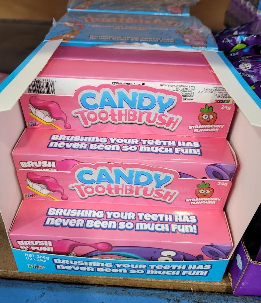A photo of a brihgt pink candy box labelled "Candy Toothbrush" with additional text "Brushing your teeth has never been so much fun!"