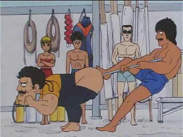 A mustached man with black hair is seen from the side, standing hunched over with his trousers dropped and the handle part of an oar sticking out of his butt (i.e. the paddle part is IN his butt). Behind him is another man with black hair and a mustache, looking like he belongs in an 80s porno and wearing nothing but swimtrunks. He has one foot on the ground, the other on the first man's butt and is trying to pull the oar out. In the background are three people looking at this: a blonde individual who looks like but may or may not be a girl, a teenage boy with black hair and a Secret Service-looking fellow with black hair and sunglasses. All are wearing swimsuits.
