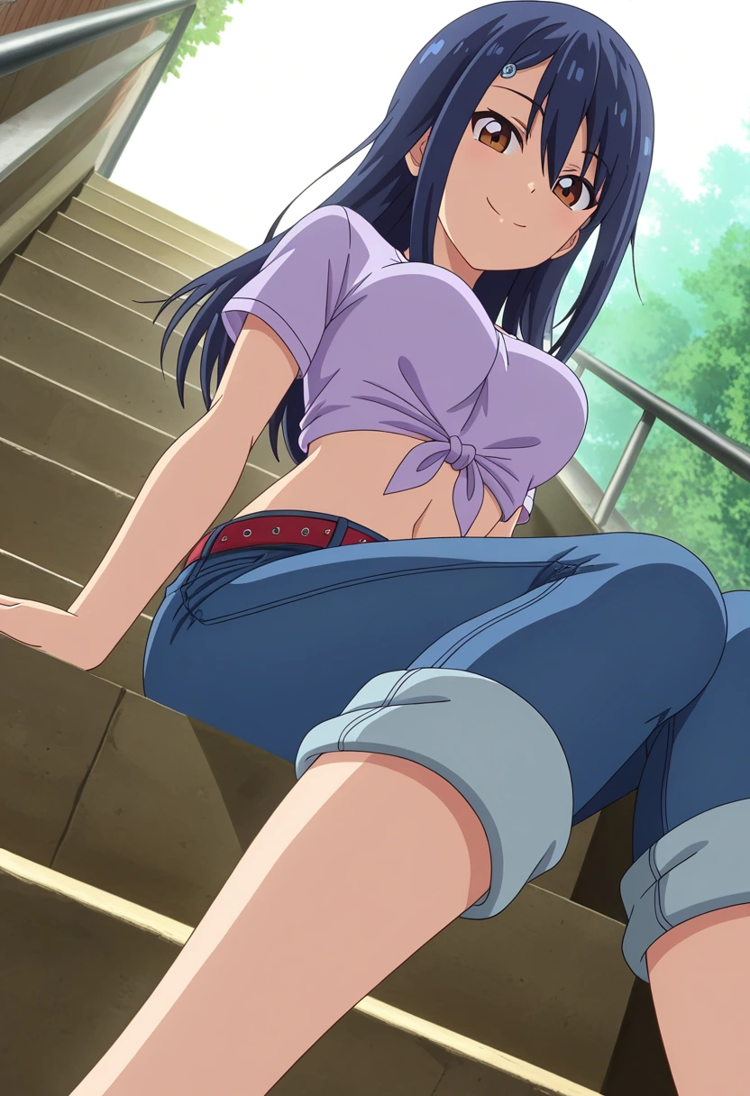 young woman with brown eyes and long, dark blue hair with a closed-mouth smile, seated on a set of stairs with her legs extending downward and her arms resting on the step under her. She is wearing a light purple, short-sleeved crop top tied in a knot at her chest, blue jeans with cuffed bottoms, and a red belt with silver studs. The steps are outdoors and receding upwards with dark metal railings, against a background of bright green foliage and a bright white sky.