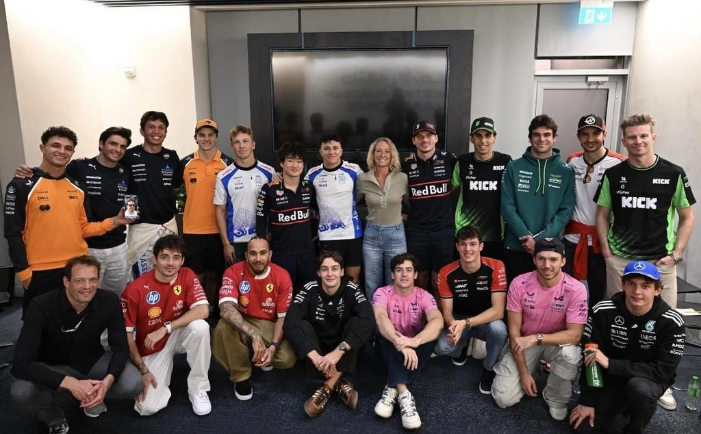 group photo of Formula 1 drivers and staff of their union organization. they are wearing teamshirts.