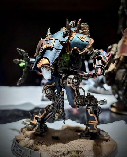 War-Dog Moirax miniature from Games Workshop armed with a Siege Claw and Conversion Beamer. The model has dark turquoise armor with dirty bronze trim and its exhaust vents glow green with leaking radiation. A nameplate on the model's base reads "Vixen".