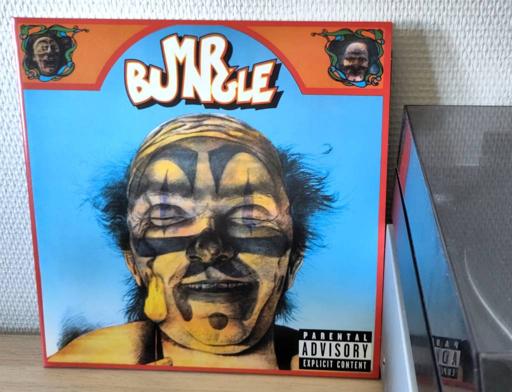 The cover is a brightly coloured art nouveau frame around a pencil illustration of a grim clown holding a lit match to his face.