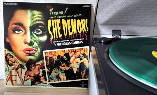 The album cover shows a schlocky '50s horror poster with sensationalist captions. The main image is a woman's face, half of which is a reptilian, green makeup. There's an uncomfortable bit of exoticism too, with bare breasted Pacific(?) natives playing bongos.