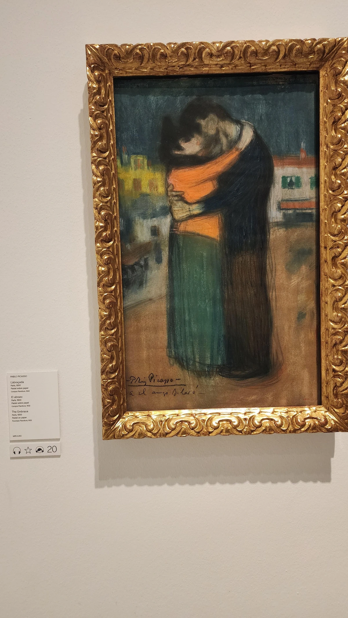 Two figures press together at the center of the canvas, their forms blending into one mass. The woman in warm fire orange — her green skirt and dark hair vivid against the man, who recedes into dark blues and brown pants. Their faces stare into each other. The background is an outdoor river scene with homes on the horizon.