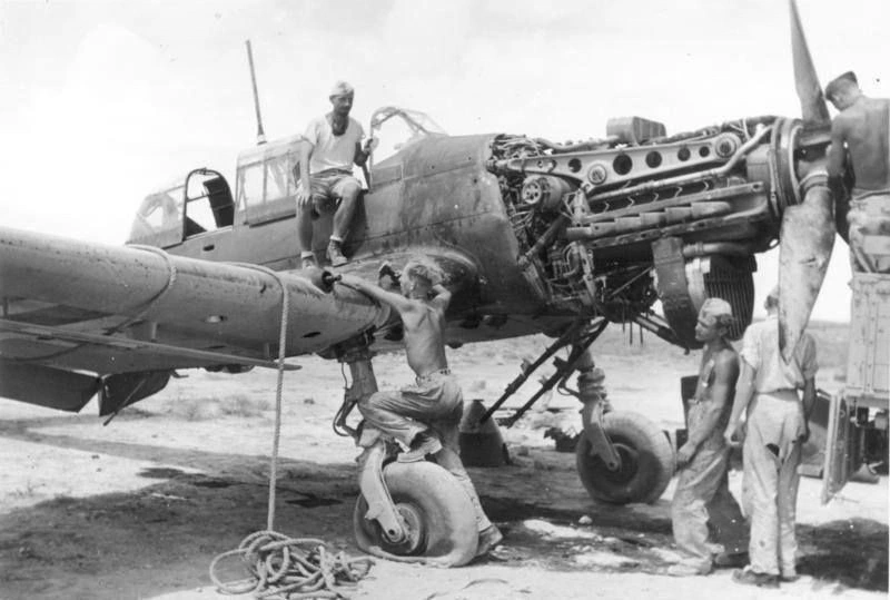 Mechanics working on a Nazi Stuka plane with a flat tire in North Africa, WW2, 1941?