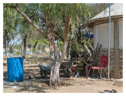 A red coca cola chair next to some wheelbarrows and barrels