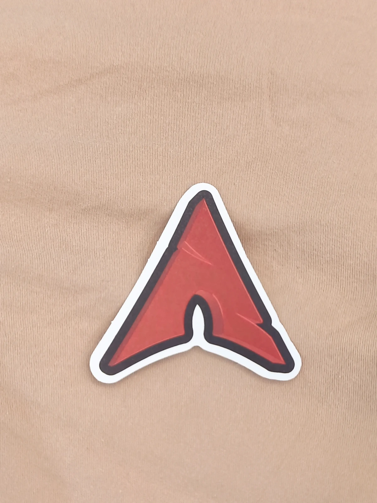 A sticker of a red version of the Arch Linux log