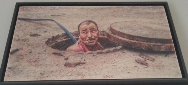 Image of a man appearing rugged from a manhole with a cigarette in his mouth