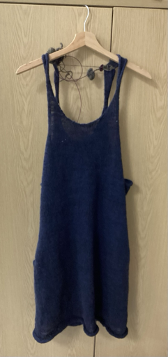A knitted blue dress against a wooden background.